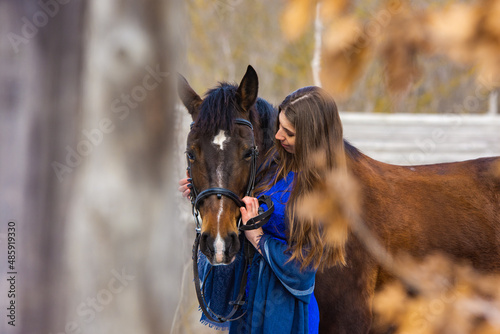 Touching portrait of a girl in a blue dress with a horse