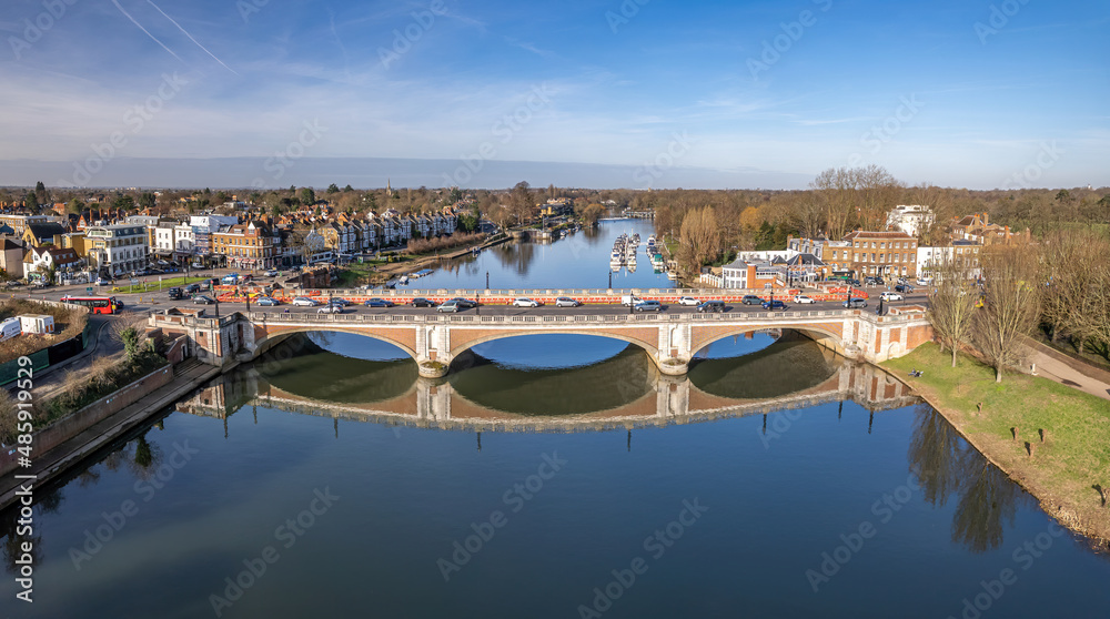 Aerial view of Hampton Court Bridge on the River Thames.Hampton Court Bridge is a Grade II listed bridge in England approximately north–south between Hampton, London and East Molesey. Aerial view of Hampton Court Bridge on the River Thames.Hampton Court Bridge is a Grade II listed bridge in England approximately north–south between Hampton, London and East Molesey.