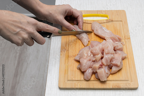 a woman on a cutting board cuts chicken meat into small pieces