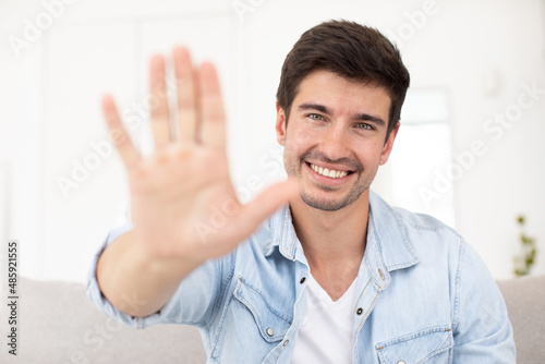 Front view on man showing greeting gesture to laptop camera starting video conference with friend or partner using video call chat