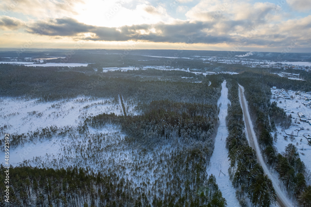 Obraz premium aerial view forest tundra taiga road in the forest in winter on a sunny frosty day in siberia small village. High quality photo