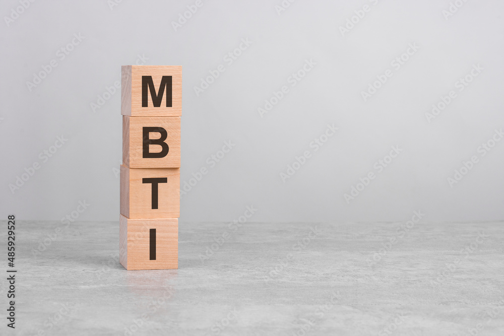 wooden cube on a concrete surface with text MBTI, copy space on right for design, gray background wooden cube on a concrete surface with text MBTI, copy space on right for design, gray background