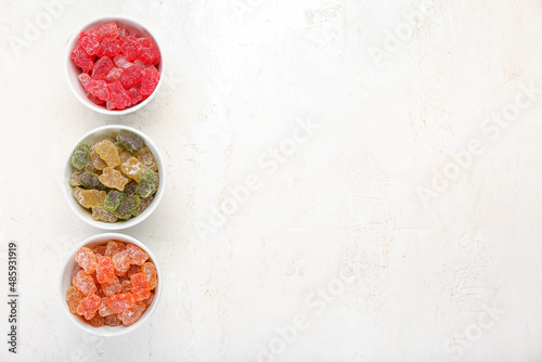 Bowls with tasty jelly bears on light background