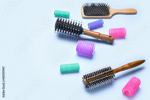 Different hair brushes and curlers on blue background