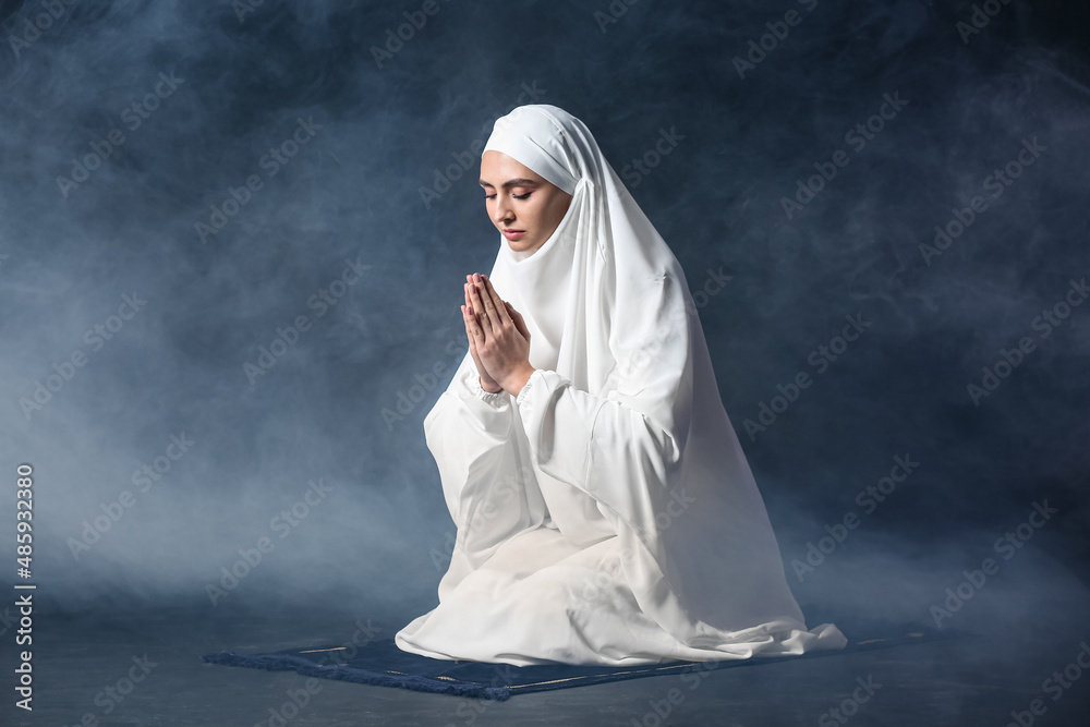 Muslim woman praying on dark background