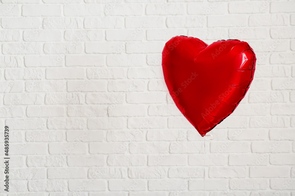 Heart shaped air balloon for Valentine's day on white brick wall background Heart shaped air balloon for Valentine's day on white brick wall background
