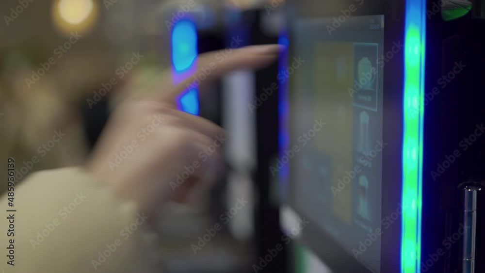A woman uses a vending machine to make coffee. Coffee machine in a coffee shop.