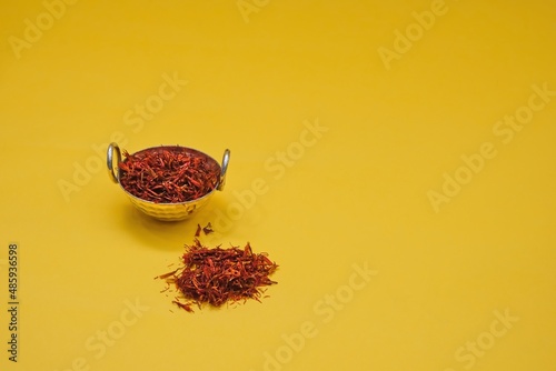 Dried rich scarlet red threads stigmas of organic persian saffron sargol spice in vintage silver spice bowl on yellow background. Pure iranian premium saffron. photo