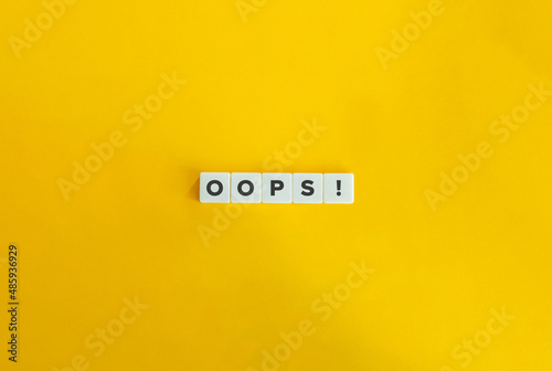 Oops word on letter tiles on bright orange background. Minimal aesthetics.