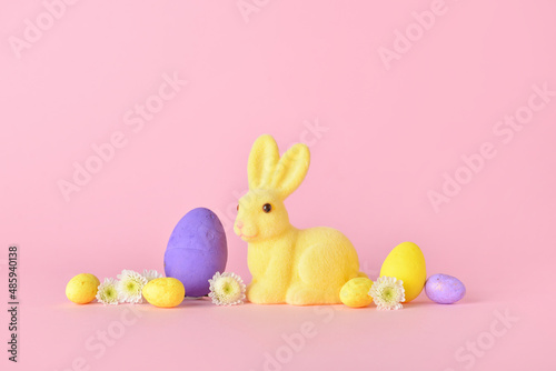 Cute Easter bunny with eggs and flowers on pink background