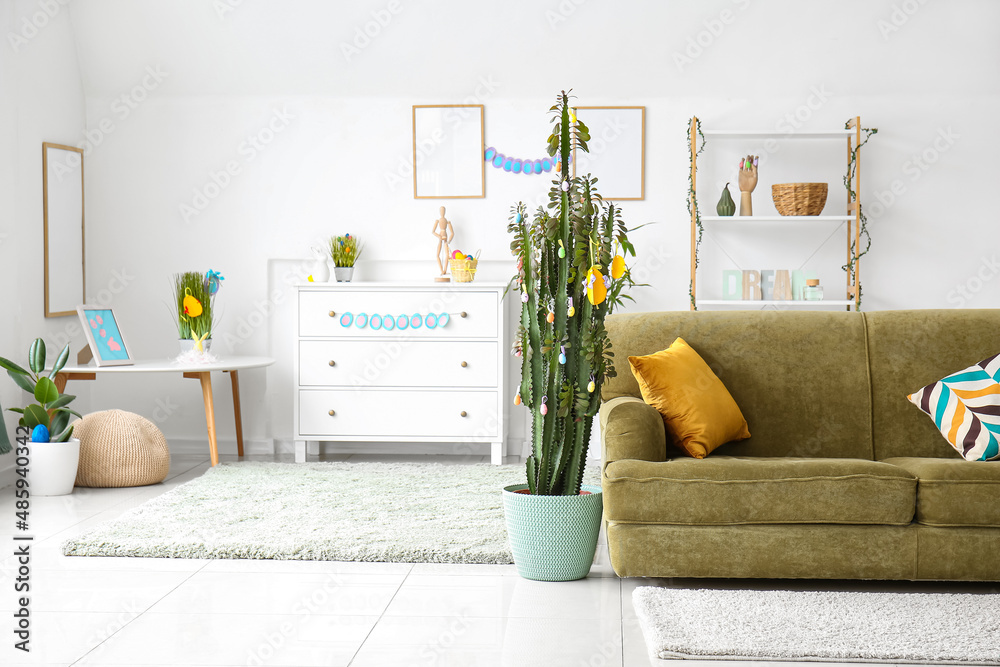 Obraz premium Interior of light living room with green sofa, cactus and Easter eggs