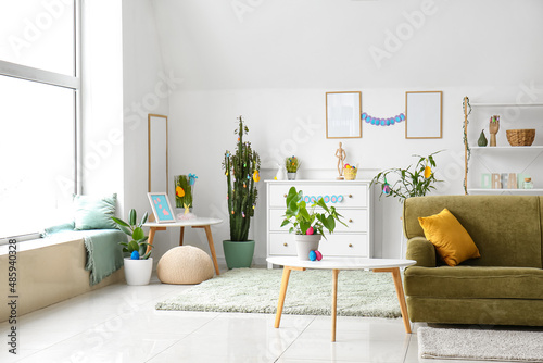 Interior of light living room with green sofa and Easter eggs