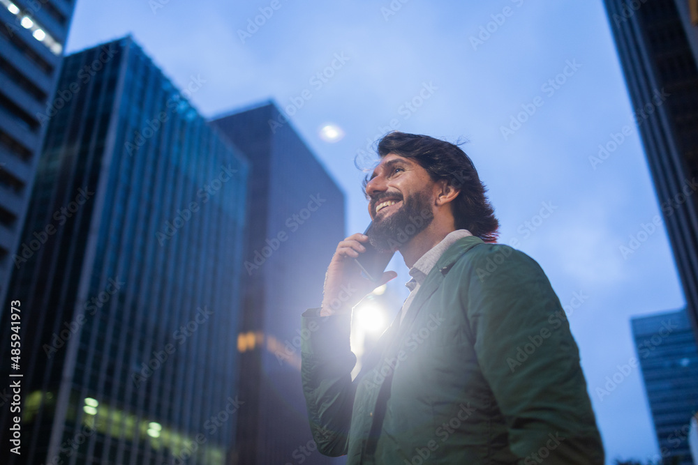 View of young man using a smartphone at night time with city view landscape in the background. High quality photo View of young man using a smartphone at night time with city view landscape in the background. High quality photo