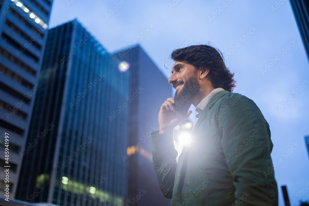 View of young man using a smartphone at night time with city view landscape in the background. High quality photo View of young man using a smartphone at night time with city view landscape in the background. High quality photo