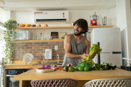 Happy and healthy young man meal prepping whole vegetarian meal in the kitchen. High quality photo