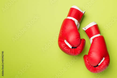 Pair of red boxing gloves on color background. Top view © Liami