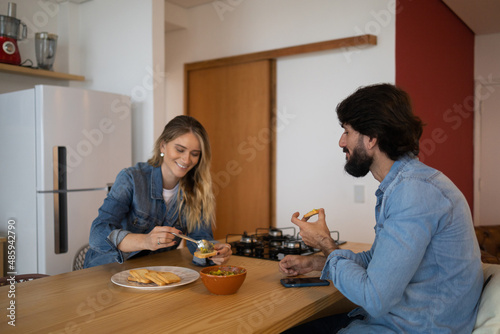 Young couple in love eating a super healthy guacamole salad with whole toast in the kitchen. High quality photo