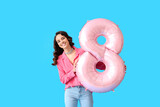 Smiling young woman with big balloon in shape of figure 8 on blue background. International Women's Day