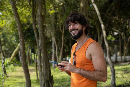 Young man at a park on a beautiful sunny day with mobile phone.