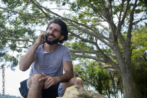 Young man at a park on a beautiful sunny day with mobile phone. © Buonaventura