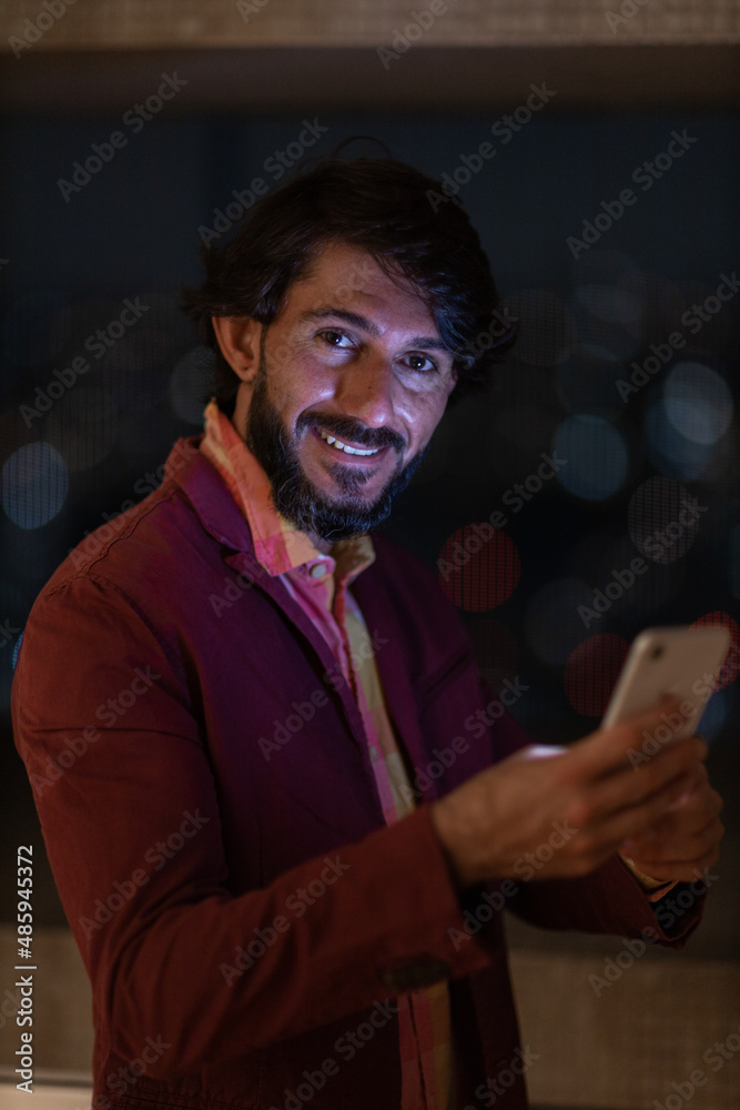 Side view of young man using a smartphone at night time with city view landscape in the background. High quality photo Side view of young man using a smartphone at night time with city view landscape in the background. High quality photo