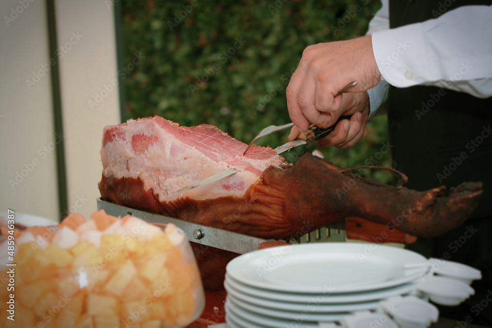 Detail of a butler at a ceremony cutting slices of Iberian ham.