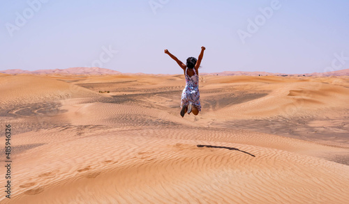 Brunette woman jumping happily in the desert
