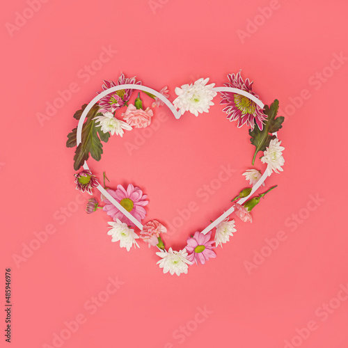 Heart-shaped copying space decorated with various real flowers. Spring concept on a pastel background. Valentine or female background design day. Symbol of a happy anniversary. Minimum flat birth.