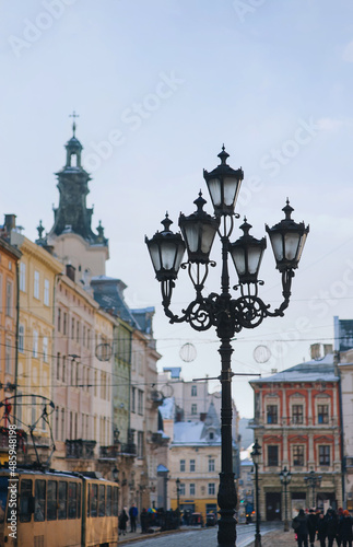 Big old curly black vintage lantern in the historical center of Lviv against the blue sky. Winter city concept.