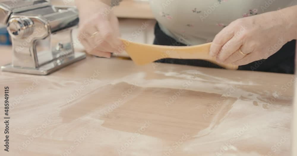 Senior cook hand rolls flour pasta dough use kitchen tool in close up Senior cook hand rolls flour pasta dough use kitchen tool in close up