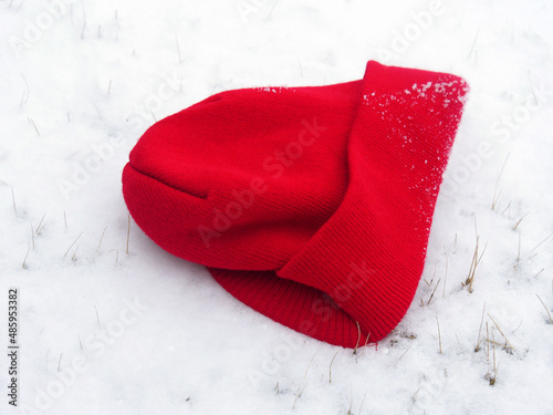 Close up, side view of a red beannie cap on a snow-covered ground