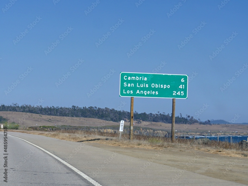 Roadside sign and distances to Cambria, San Luis Obispo and Los Angeles along Highway 1, California.