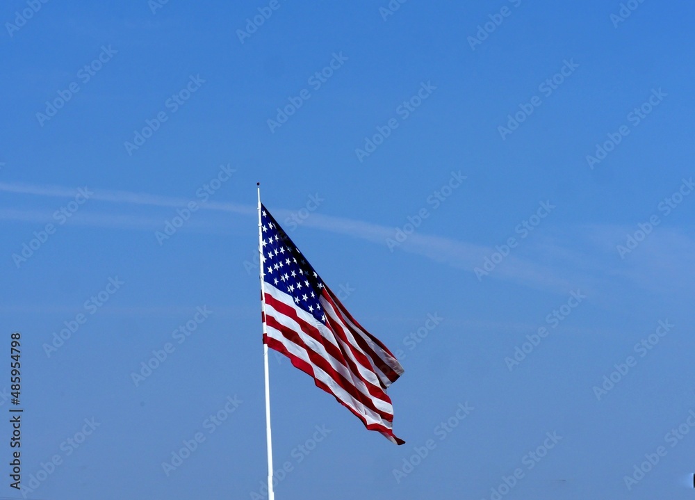 Wide shot of a United States flag with light blue skies in the background