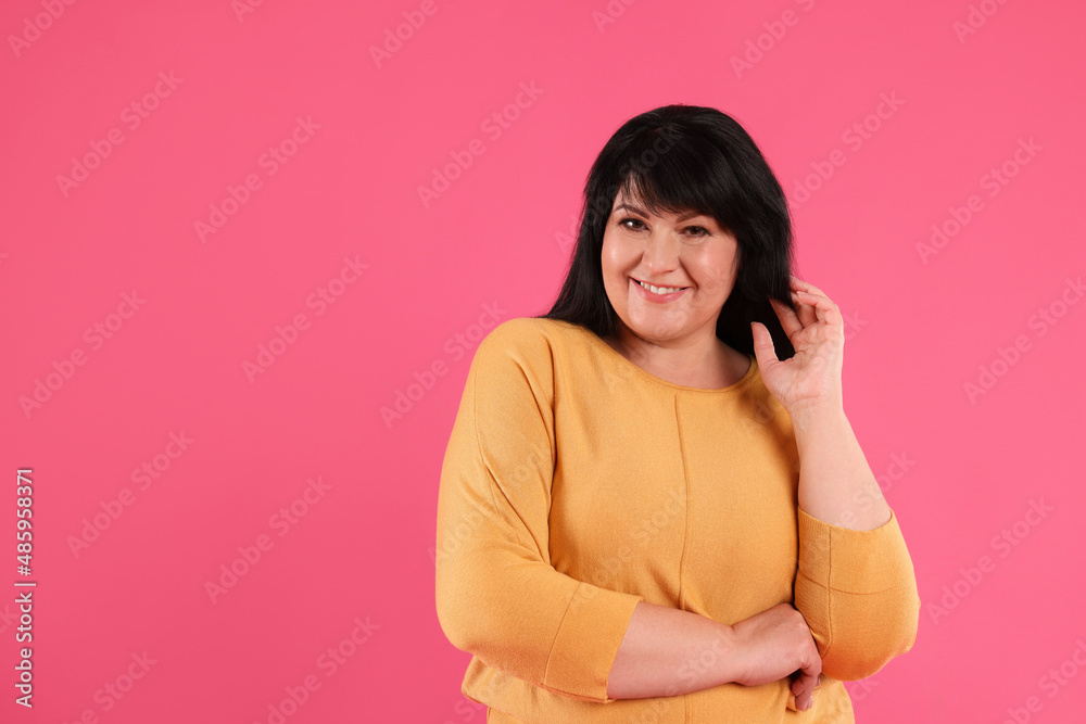 Beautiful overweight mature woman with charming smile on pink background. Space for text