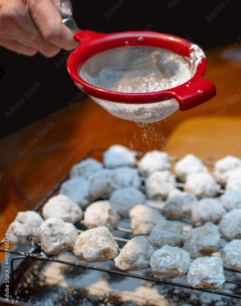 Dusting snowball cookies with powdered sugar. these are also called