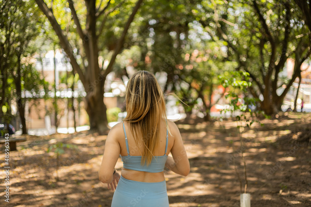 Naklejka premium Young woman running and jogging at a park outdoors. Athlete female person during workout. High quality photo