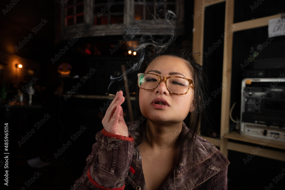 Asian girl smoking a weed joint getting high inhaling and exhaling weed