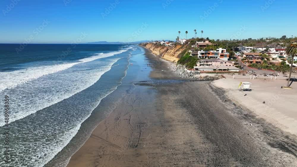 Aerial drone shot along scenic coastline of Encinitas in California, USA with the view of waves crashing on the beach on a bright sunny day. Aerial drone shot along scenic coastline of Encinitas in California, USA with the view of waves crashing on the beach on a bright sunny day.