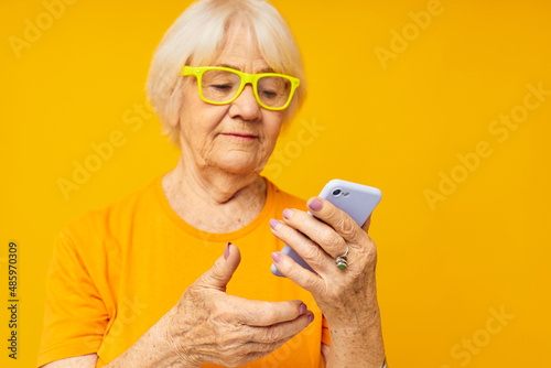 Portrait of an old friendly woman happy lifestyle in yellow t-shirts with phone technologies