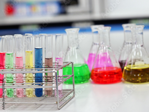The Erlenmeyer conical Flasks and test tubes with rack on bench laboratory, with colorful solvent for testing indicator, titration experiment, acidity, alkalinity, and hardness in waste water sample.