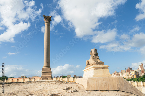 The famous Pompey pillar with sphinx in the Upper Egyptian city of Alexandria. A popular travel destination. day and blue sky. A nice long exposure with moving clouds. photo