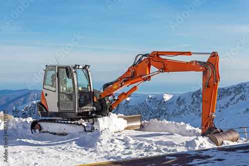 Excavator for clearing snow on tops of snowy mountains, ski resort.