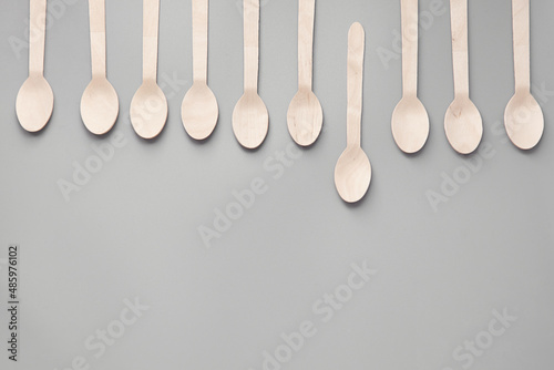 Wooden spoon, fork, paper cups gray background. Disposable tableware made of natural materials. The concept of a zero waste, sustainable lifestyle. Eco-friendly disposable tableware