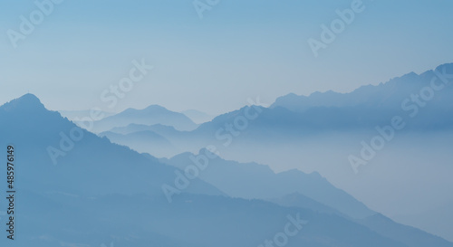 Amazing aerial landscape at the Alps in winter season. Foggy and humidity in the air. Italian alps. Silhouette of the mountains and summits