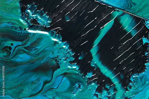Fluid Art. Green and blue abstract waves on black background. Marble effect background or texture