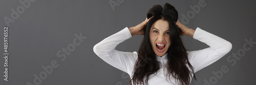 Aggressive young woman screaming and holding head with hands portrait