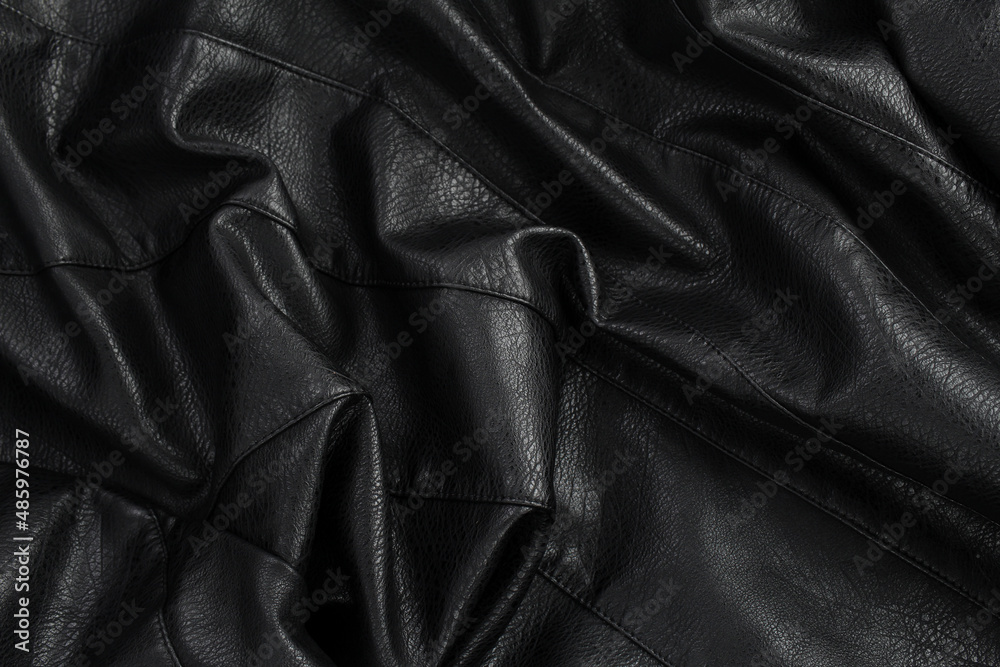 Black crumpled leather jacket. Textured background made of smooth leather fabric. Black crumpled leather jacket. Textured background made of smooth leather fabric.