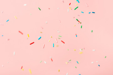 flying colorful sprinkles over pink background