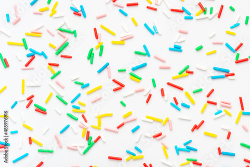 flat lay of colorful sprinkles over white background, festive decoration for ...
