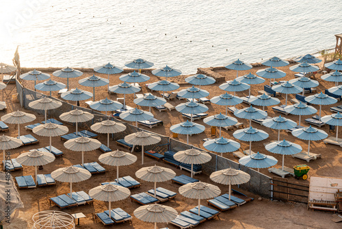 A beach club in morning with no people and blue and beach umbrellas photo